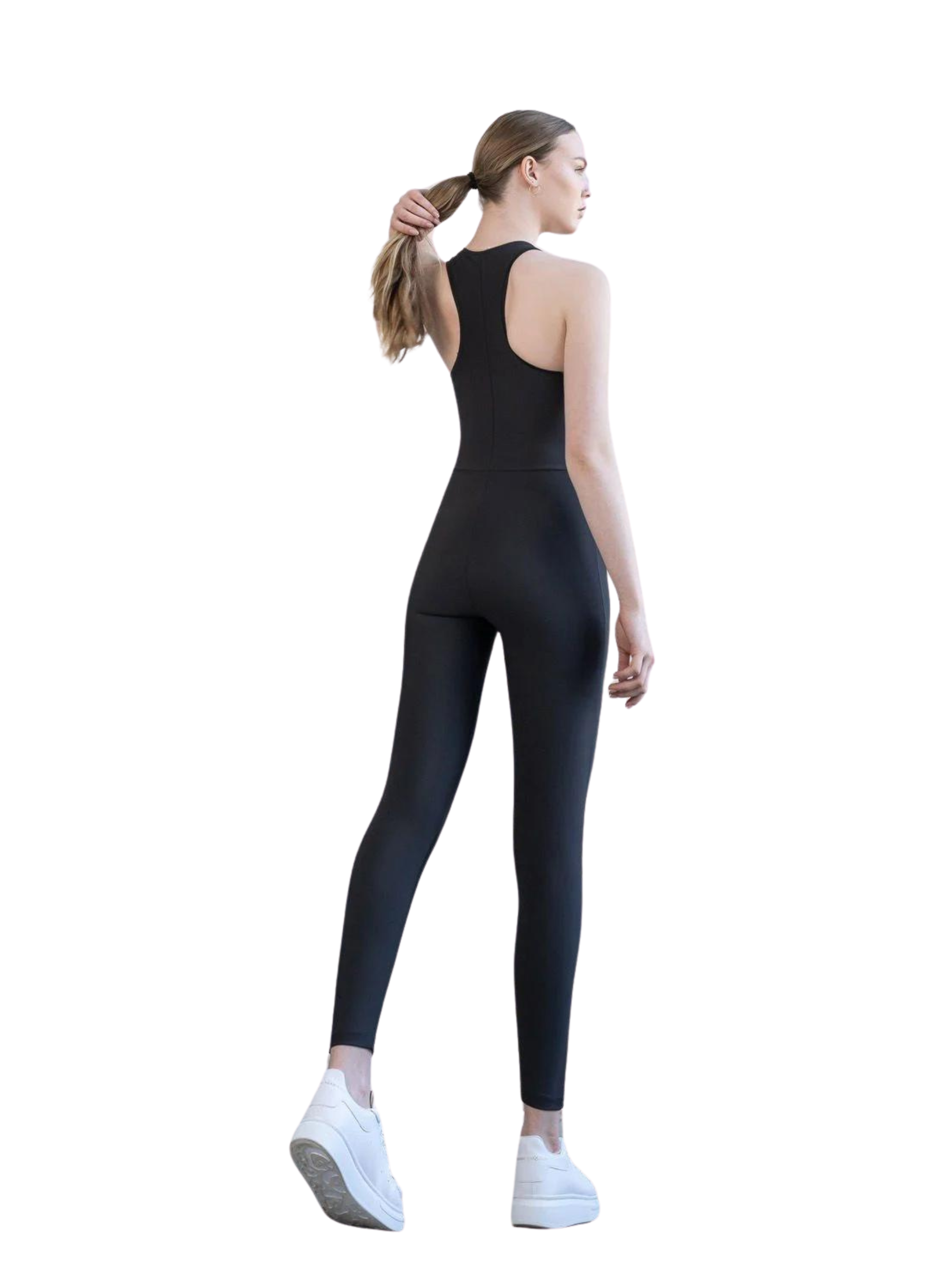 Frau in Lisminas 2852 Zipper Jumpsuit in Schwarz und weißen Turnschuhen, abgewandt, hält Pferdeschwanz.